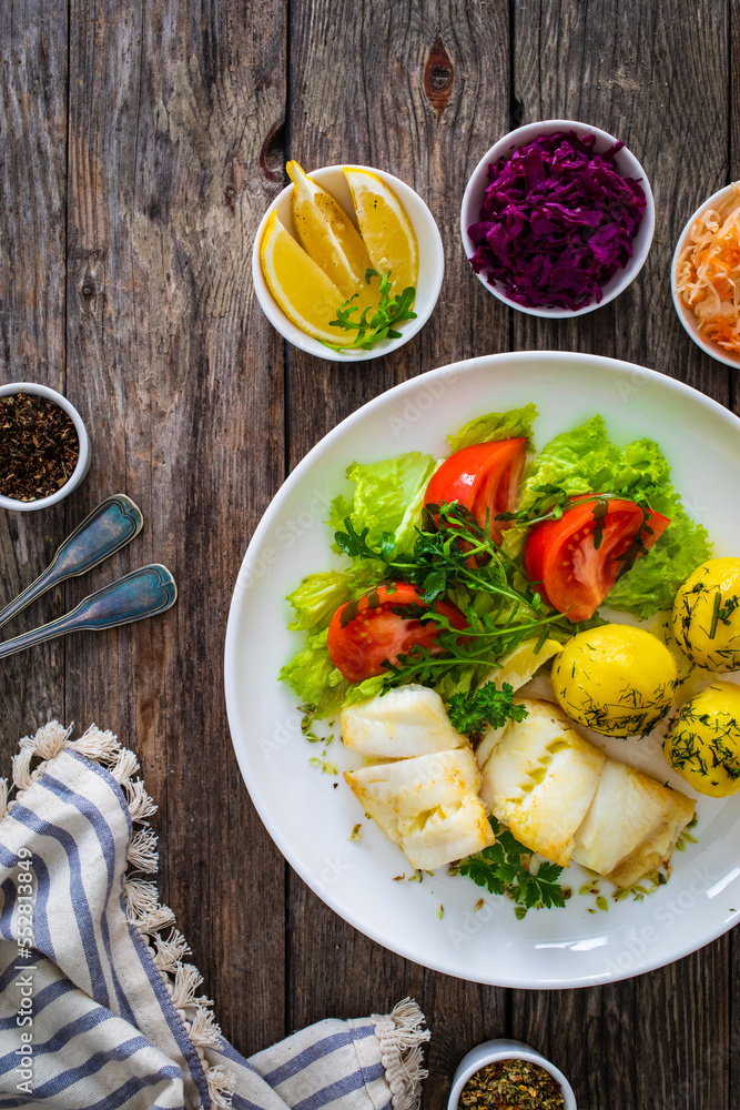 Fish dish - fried halibut with boiled potatoes and fresh vegetables on wooden table
Fish dish - fried halibut with boiled potatoes and fresh vegetables on wooden table
