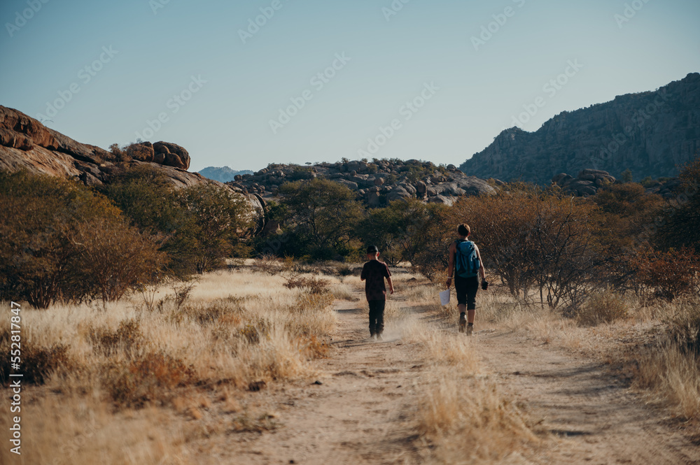 Mutter wandert mit ihrem Sohn im Licht der langsam untergehenden Sonne durch das Erongogebirge, Namibia