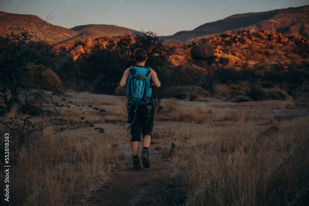 Frau wandert bei Sonnenuntergang durch das Erongo Gebirge, Namibia Frau wandert bei Sonnenuntergang durch das Erongo Gebirge, Namibia