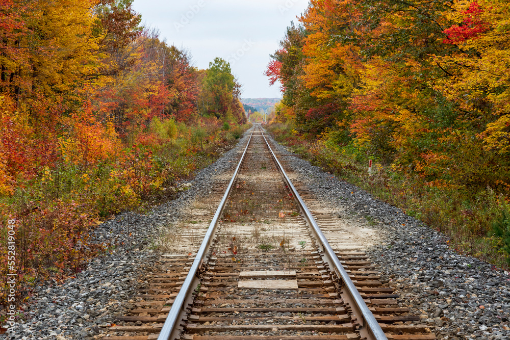 Sainte Ursule, Canada,  10-12-2022.  Railway with fall colors in background near Sainte Ursule Waterfall. Canada.