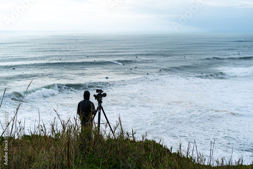 Photography Rear view of videographer filming surfers in Nazare Surfing Challenge