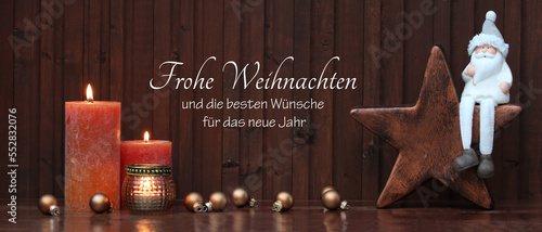 Weihnachtskarte: Rustikale Weihnachtsdekoration  Kerzen mit Nikolaus auf einem Stern sitzend vor einer  Holzwand dekoriert. Mit dem Text Frohe Weihnachten und die besten Wünsche für das neue Jahr. photo