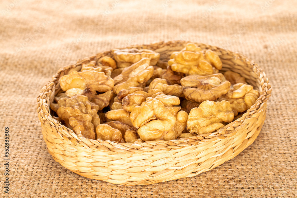 A few peeled walnuts in a straw plate on a jute cloth, macro. A few peeled walnuts in a straw plate on a jute cloth, macro.