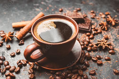 Fresh brewed black coffee in a cup on dark background with coffee beans and chocolate pieces
