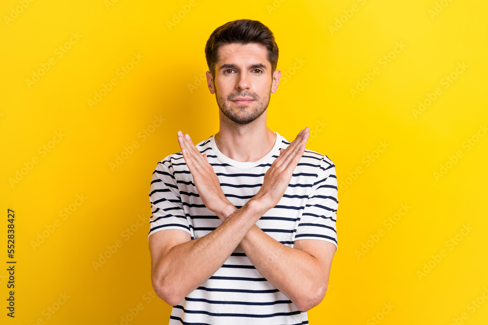 Portrait of calm concentrated person crossed arms demonstrate stop gesture isolated on yellow color background Portrait of calm concentrated person crossed arms demonstrate stop gesture isolated on yellow color background