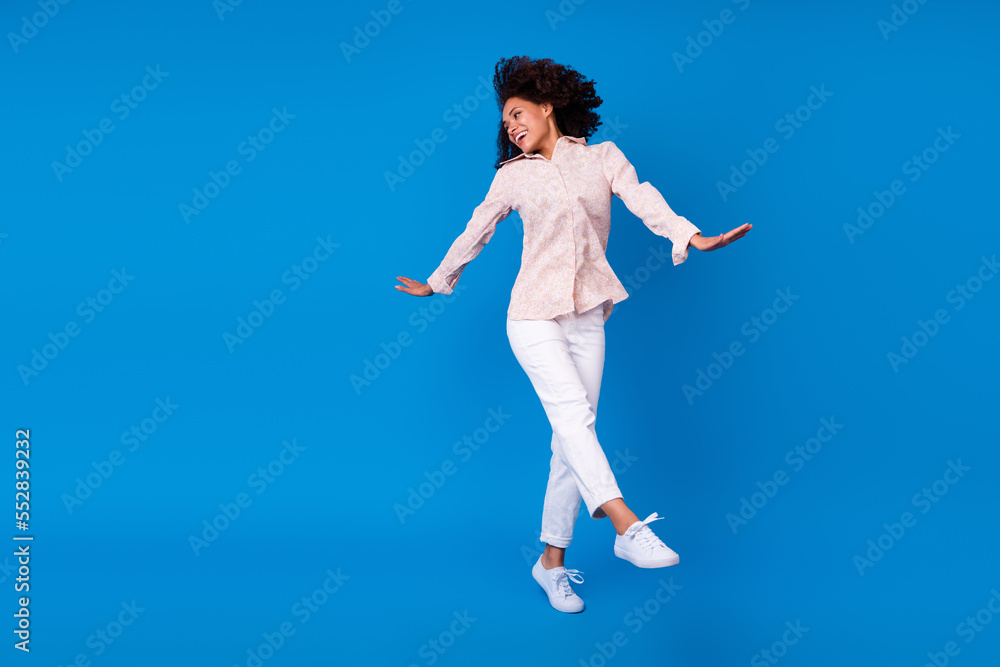 Full length photo of pretty shiny lady wear pink shirt dancing walking empty space isolated blue color background Full length photo of pretty shiny lady wear pink shirt dancing walking empty space isolated blue color background