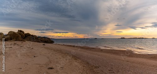 panorama view of a golden sand beach at sunset with calm ocean water and red granite rocks © makasana photo