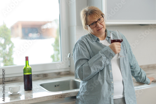 Woman drinking a glass of wine in a modern kitchen photo