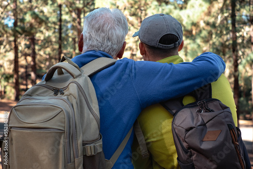 Back view of a couple of senior grandfather and young grandson hiking together in the woods sharing the same passion for nature and healthy lifestyle. © luciano