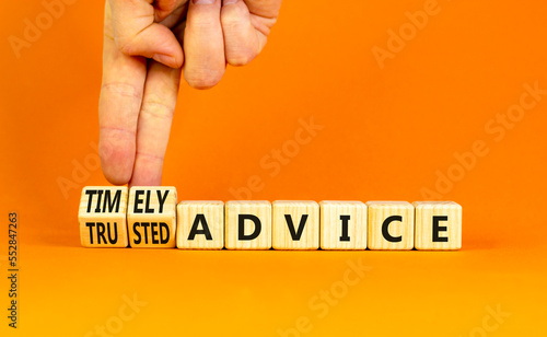 Timely or trusted advice symbol. Concept words Timely advice and Trusted advice on wooden cubes. Businessman hand. Beautiful orange background. Business timely or trusted advice concept. Copy space.