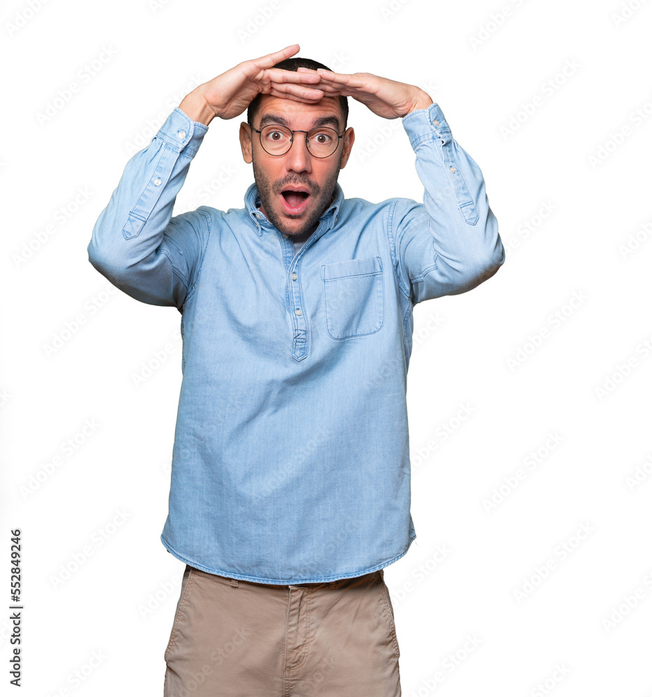 Astonished young man with a gesture of looking far Astonished young man with a gesture of looking far