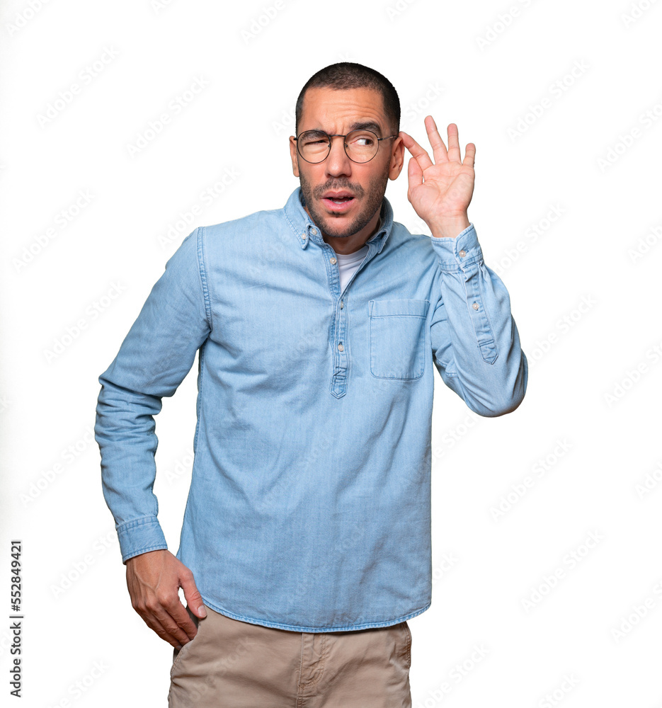 Concentrated young man making a gesture of trying to hear something Concentrated young man making a gesture of trying to hear something