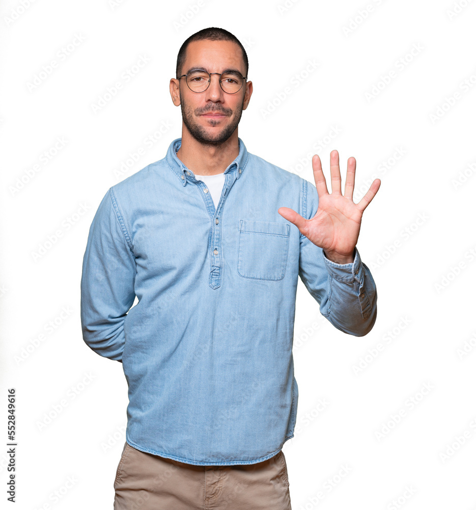 Young man making a number five gesture Young man making a number five gesture
