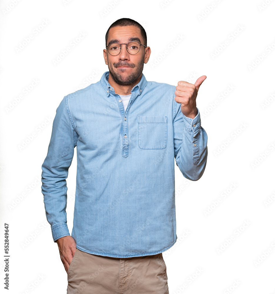 Hesitant young man gesturing that everything is fine Hesitant young man gesturing that everything is fine
