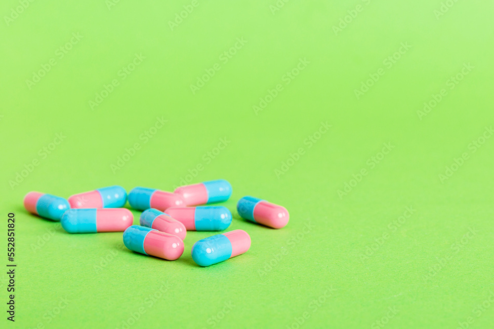 Heap of pink and blue pills on colored background. Tablets scattered on a table. Pile of red soft gelatin capsule. Vitamins and dietary supplements concept Heap of pink and blue pills on colored background. Tablets scattered on a table. Pile of red soft gelatin capsule. Vitamins and dietary supplements concept