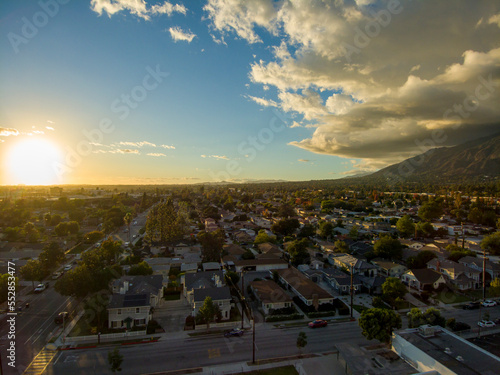 aerial shot of homes, apartments, and shops in the city skyline with cars driving on the street lush green trees at sunset in Monrovia California USA photo