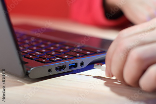 inserting a usb cable into a laptop on a table