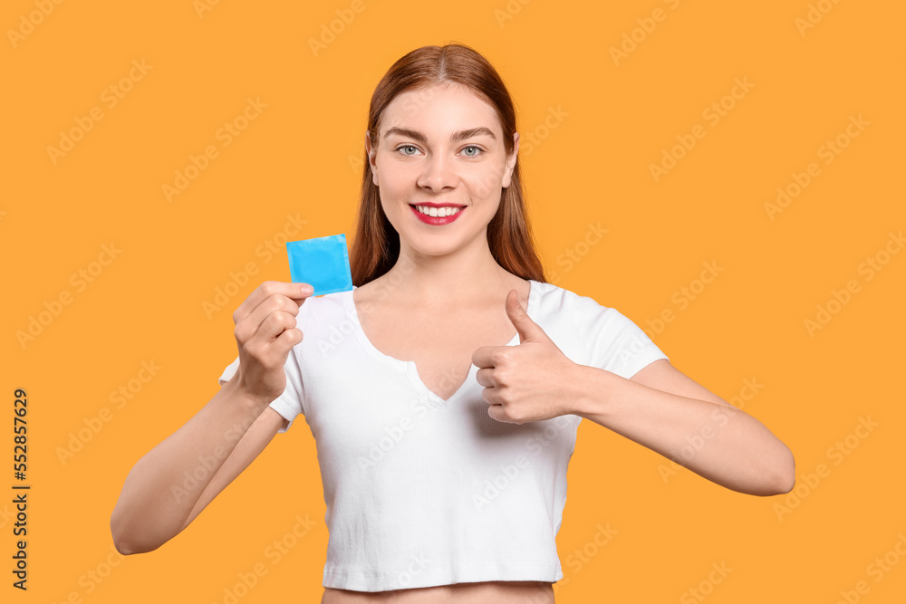 Woman holding with condom showing thumb up on yellow background. Safe sex Woman holding with condom showing thumb up on yellow background. Safe sex