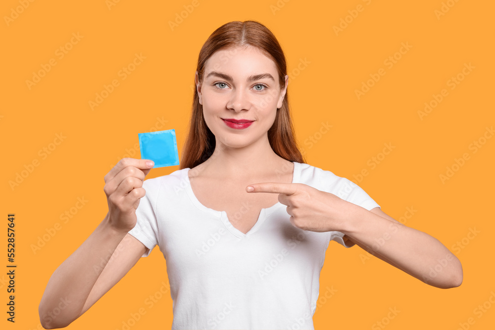 Woman holding condom on yellow background. Safe sex Woman holding condom on yellow background. Safe sex