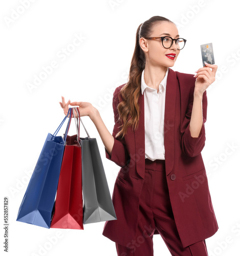 Stylish young businesswoman with shopping bags and credit card on white background