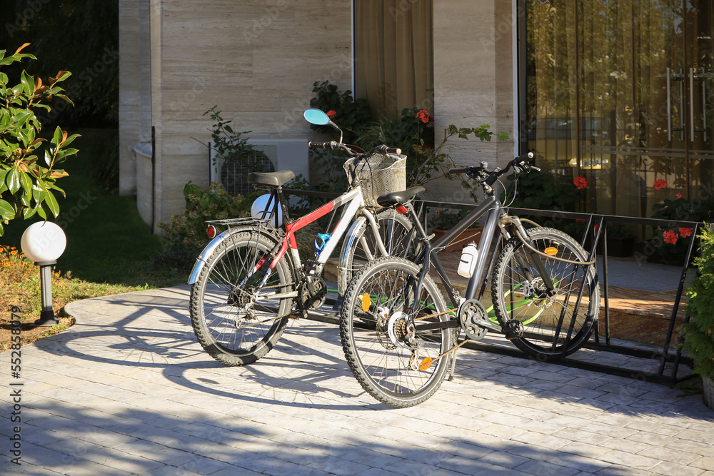 Parking rack with modern bicycles near building outdoors