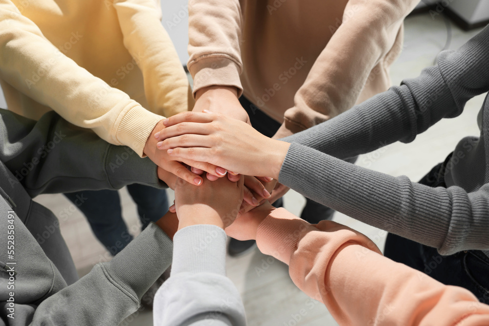 Fototapeta premium Group of people holding hands together indoors, above view. Unity concept