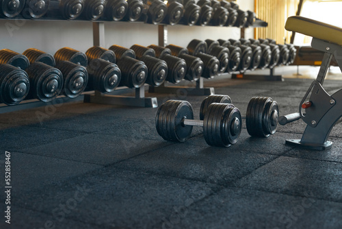 Dumbbell Rows. Sports equipment and dumbbells. Interior of the gym. Camera focus on the dumbbells lying on the floor. Copy space on the bottom