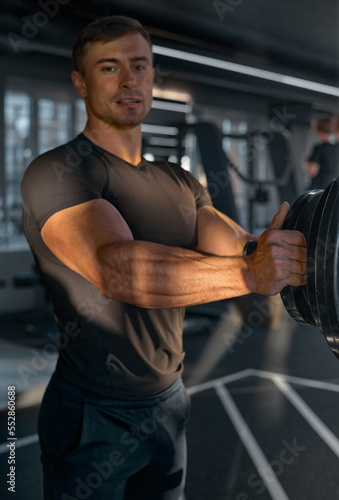 Workout in the gym. Strong and muscular arms of a man. The concept of a healthy body, a strong man. A sunbeam shines on the muscles of the arm in the foreground. Template for watches and accessories