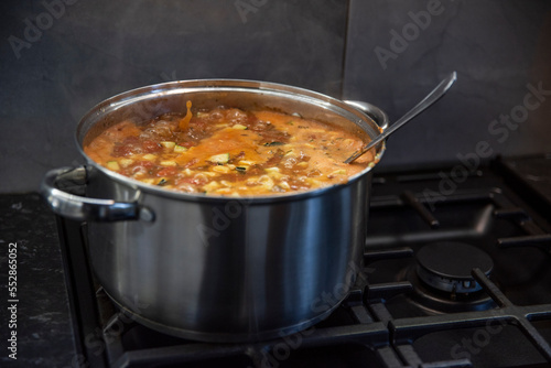 Gotująca się zupa toskańska na czarnej kuchence gazowej photo