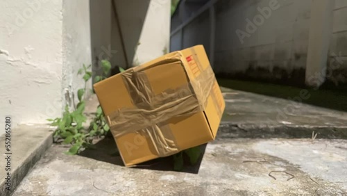 Brown box package falling on ground slow motion on a sunny day