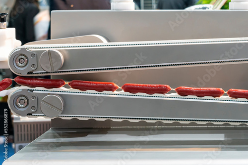 фотографія sausage chain during produced by past on conveyor system of automatic machine fo
