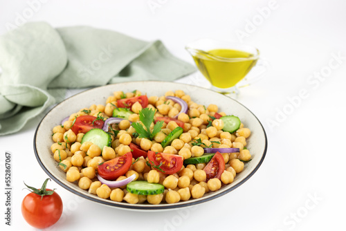 Chickpea salad with tomatoes, cucumbers, onions and olive oil on a white background. Selective focus. Oriental and Mediterranean cuisine. 