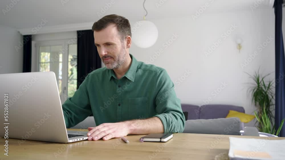 Mid adult man using laptop for remote work at home Mid adult man using laptop for remote work at home
