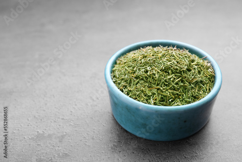 Bowl with dried thyme on grey table, closeup. Space for text