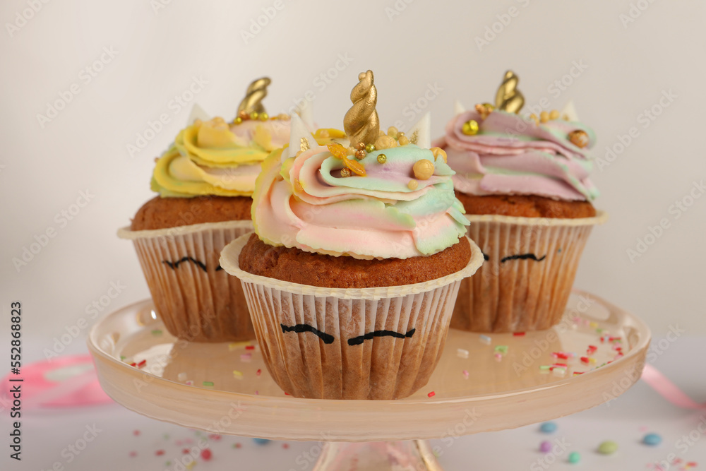 Dessert stand with cute sweet unicorn cupcakes on white background, closeup Dessert stand with cute sweet unicorn cupcakes on white background, closeup