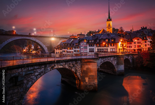 Incredible vivid cityscape. Scenic view Historical Old Town of Bern city with colorful sky, view on bridges over Aare river and church tower during dramatic sunset. Bern. Switzerland. Europe photo