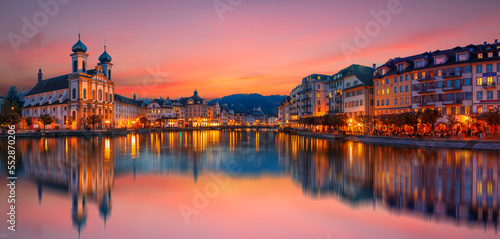 Scenic evening panorama view of the Old Town medieval architecture in Lucerne, Switzerland. Dramatic scene with Reuss river and Jesuit church. Wonderful vivid cityscape during sunset