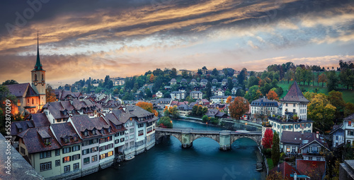 Wonderful vivid cityscape. Scenic view Historical Old Town of Bern city, tiled roofs, bridges over Aare river and church tower during dramatic sunset. Bern. Switzerland. Europe.