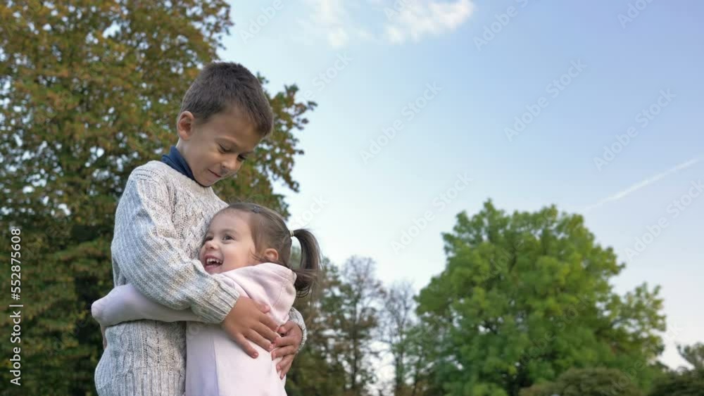 Little girl runs towards her older brother and hugs him. Little girl runs towards her older brother and hugs him.