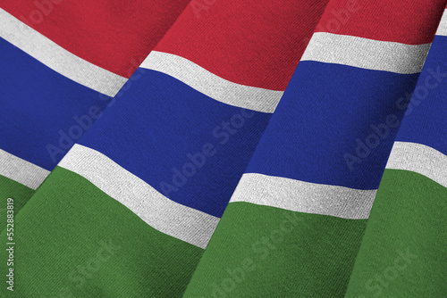 Gambia flag with big folds waving close up under the studio light indoors. The official symbols and colors in fabric banner photo