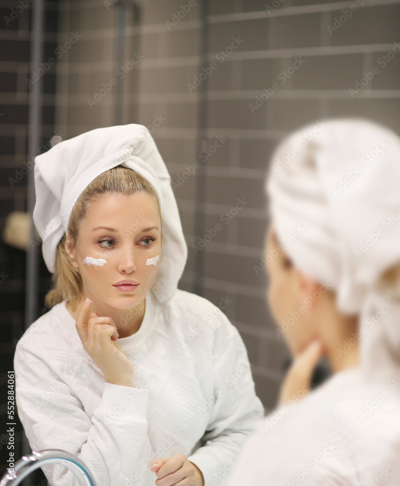 Woman looking in the mirror Applying the cream..Magic anti-aging cream Woman looking in the mirror Applying the cream..Magic anti-aging cream