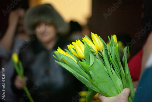 Yellow flowers in hands. Bouquet of flowers for artist. Guests after event.