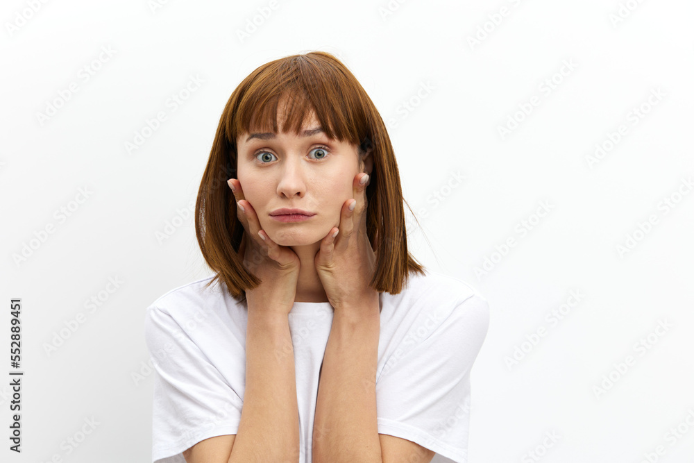 a funny, emotional woman stands on a white background in a white T-shirt and holds it with her hands while making a funny face. Horizontal photo with an empty space for inserting an advertising layout a funny, emotional woman stands on a white background in a white T-shirt and holds it with her hands while making a funny face. Horizontal photo with an empty space for inserting an advertising layout