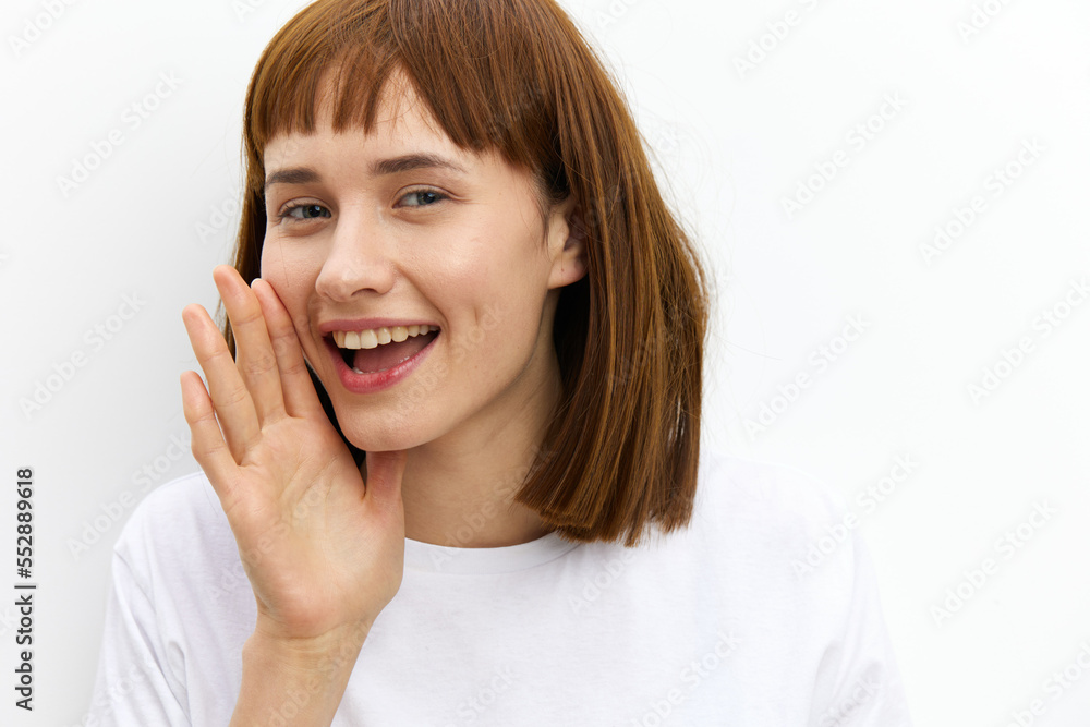 a happy, joyful woman stands in a white T-shirt, leaning towards the camera, smiling broadly as if she wants to tell a secret a happy, joyful woman stands in a white T-shirt, leaning towards the camera, smiling broadly as if she wants to tell a secret