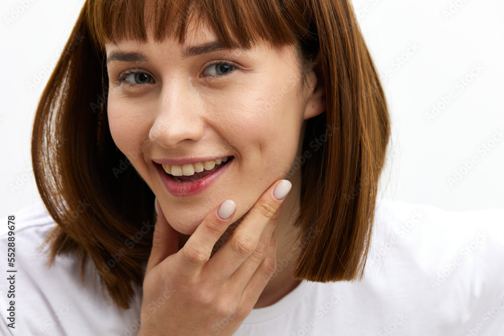 a sweet, happy woman smiles pleasantly looking at the camera standing in a white T-shirt on a light background Horizontal photo with an empty space for inserting an advertising layout a sweet, happy woman smiles pleasantly looking at the camera standing in a white T-shirt on a light background Horizontal photo with an empty space for inserting an advertising layout