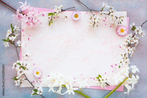 Spring hyacinth flowers, daisies, blossoming cherry plum branches and paper for text on a decorative colorful background. Congratulations on Mother's Day, birthday.