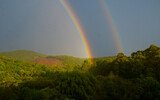 double rainbow over the mountain with forest and blue sky
