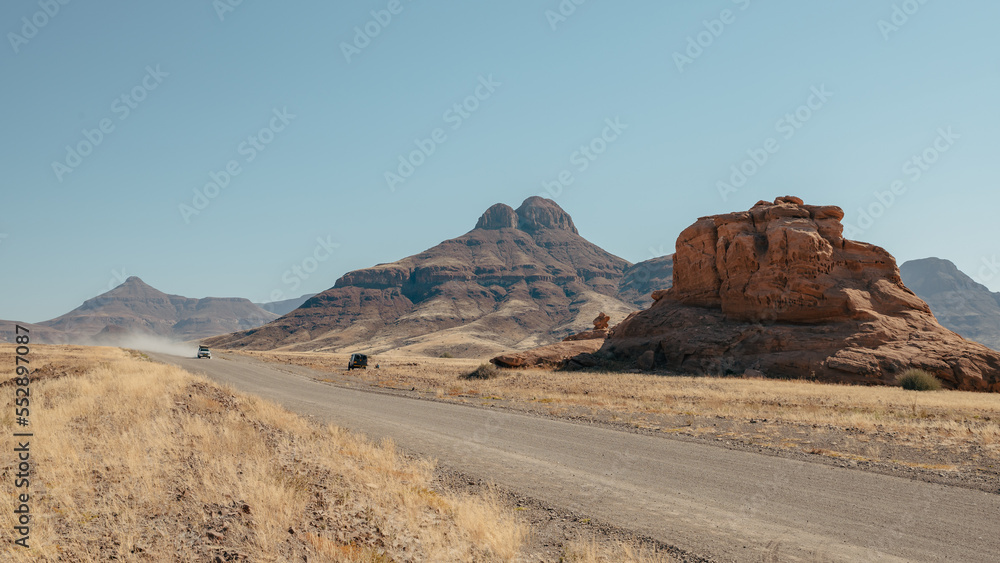Rast an einem solitären roten Felsen an einer einsamen Straße in der bergigen Landschaft des Damaralandes, Namibia