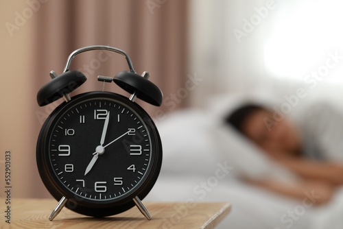 Woman sleeping in bedroom, focus on alarm clock. Space for text