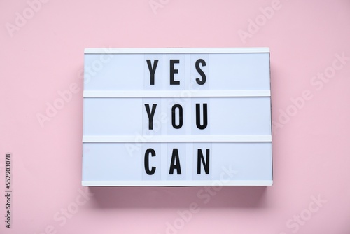 Lightbox with phrase Yes You Can on pale pink background, top view. Motivational quote